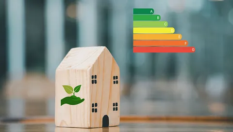 Trefigur av et hus med miljøsymbol foran energimerkeskala fra A til G